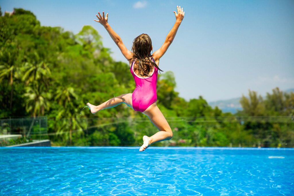 Excited girl jumping into a pool